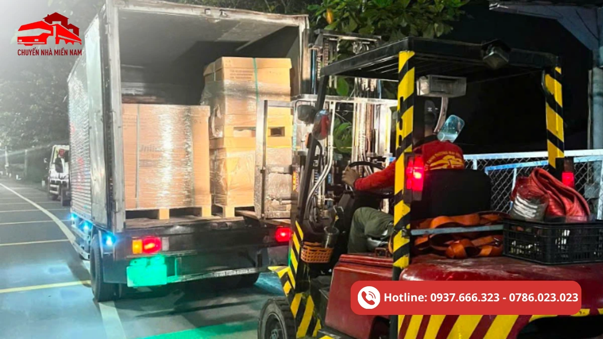 Hình ảnh thực tế dịch vụ nâng hạ hàng hóa bằng xe nâng, xử lý pallet và kiện hàng từ xe tải trong điều kiện thi công ban đêm.